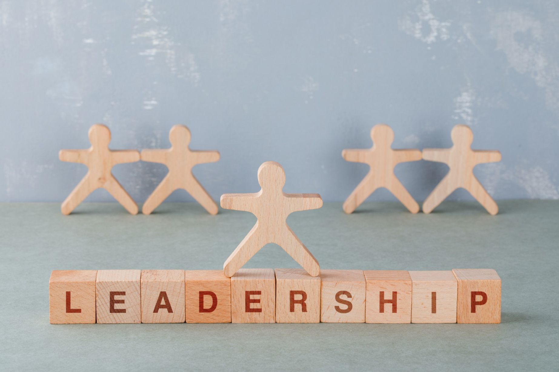 A wooden figurine standing atop blocks that spell out: LEADERSHIP.