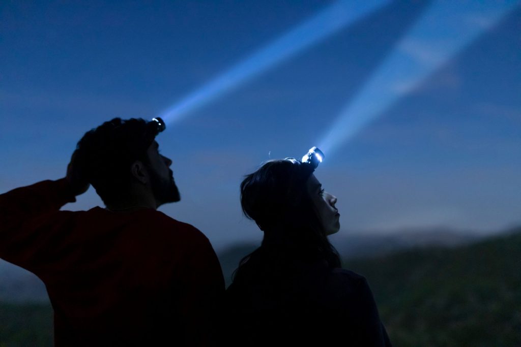 Two people wearing lights on their heads.